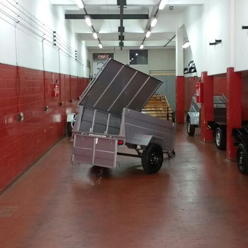 Carreta baú aberta para manutenção em ambiente interno, destacando sua estrutura reforçada e funcionalidade.