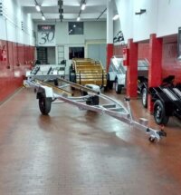 Carreta náutica galvanizada em showroom, ao lado de carretinhas para motos e carga; exemplo de carreta ideal para motos, barcos e cargas.