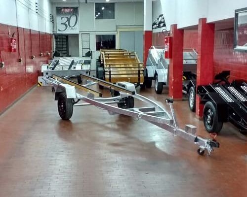 Carreta náutica galvanizada em showroom, ao lado de carretinhas para motos e carga; exemplo de carreta ideal para motos, barcos e cargas.
